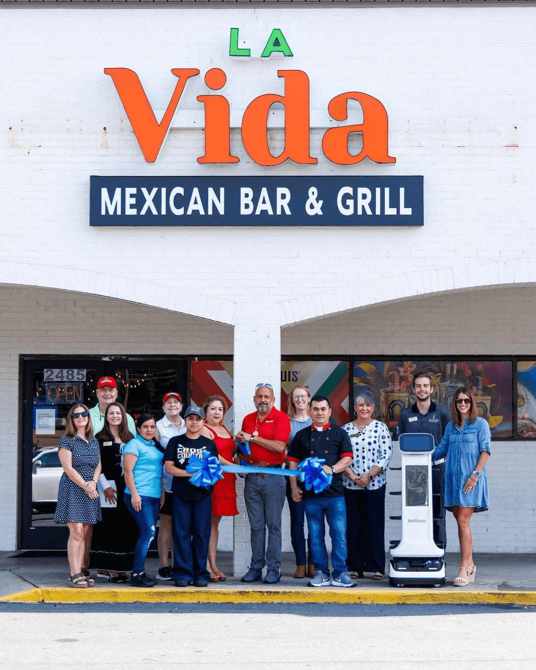 Ribbon-cutting ceremony outside La Vida Mexican Bar & Grill with the team and local chamber members